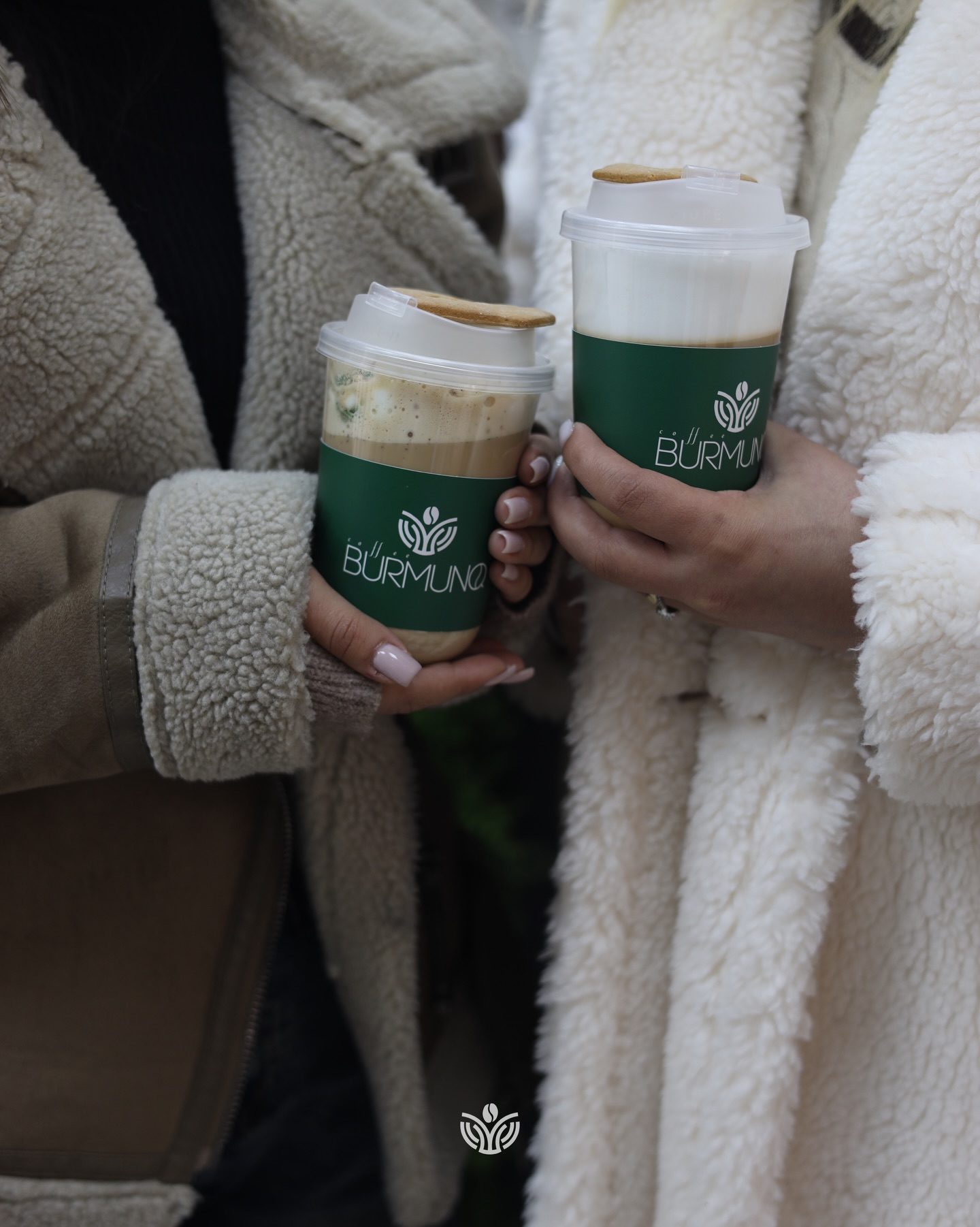 Two Coffee Burmunq takeaway cups held by friends